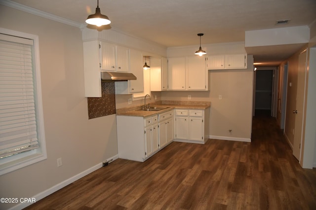 kitchen with a sink, under cabinet range hood, white cabinetry, baseboards, and dark wood-style flooring