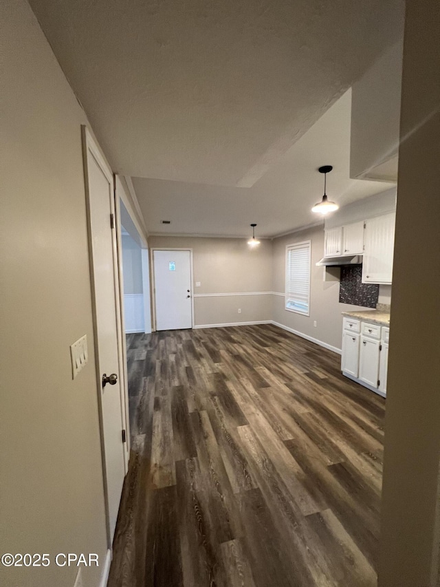 unfurnished living room featuring dark wood-type flooring and baseboards