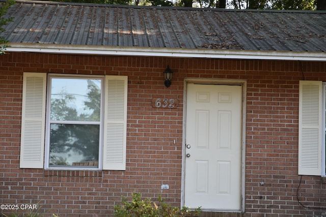 property entrance with brick siding and metal roof