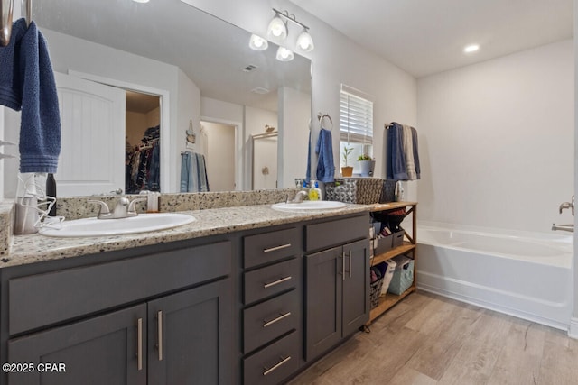 4717 Maegans Ridge Rd, Panama City, FL 32404 - bathroom featuring double vanity, wood finished floors, a garden tub, and a sink