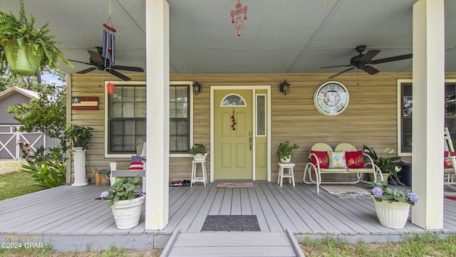 doorway to property with a porch, ceiling fan, and fence