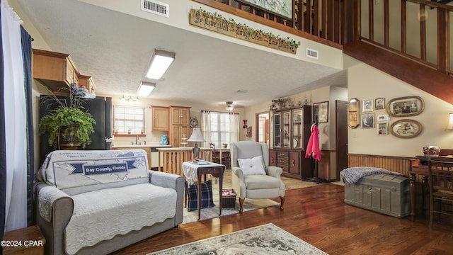 living area featuring visible vents, a wainscoted wall, and wood finished floors