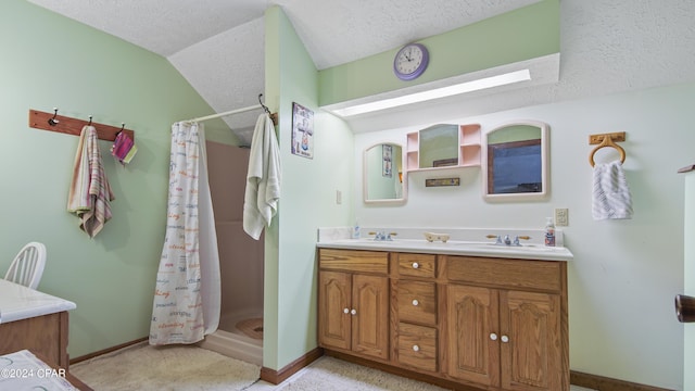 full bathroom with a shower stall, double vanity, baseboards, vaulted ceiling, and a textured ceiling