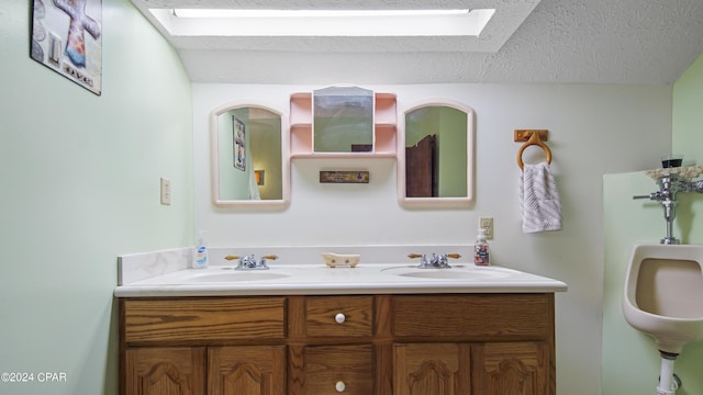 full bath featuring a skylight, a textured ceiling, and double vanity