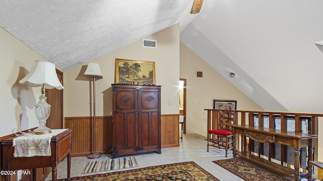 additional living space with vaulted ceiling, wainscoting, a textured ceiling, wooden walls, and carpet