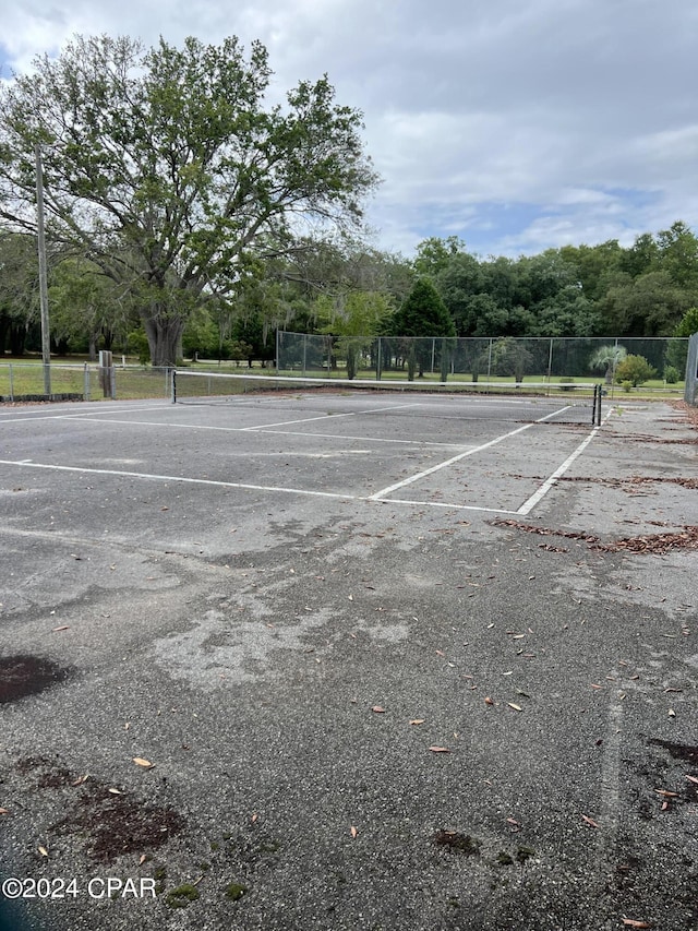 uncovered parking lot featuring fence and a tennis court