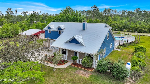 8508 S Holland Rd, Southport, FL 32409 - view of front of house featuring a chimney, a porch, metal roof, a front yard, and a garage
