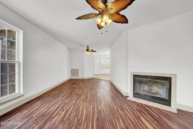 8508 S Holland Rd, Southport, FL 32409 - unfurnished living room with wood finished floors, a fireplace with flush hearth, ceiling fan, and baseboards