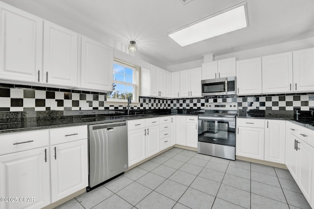 8508 S Holland Rd, Southport, FL 32409 - kitchen with appliances with stainless steel finishes, decorative backsplash, white cabinetry, a sink, and dark stone countertops
