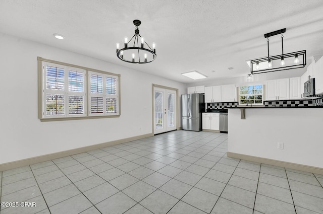 8508 S Holland Rd, Southport, FL 32409 - kitchen with stainless steel appliances, dark countertops, backsplash, a chandelier, and white cabinets