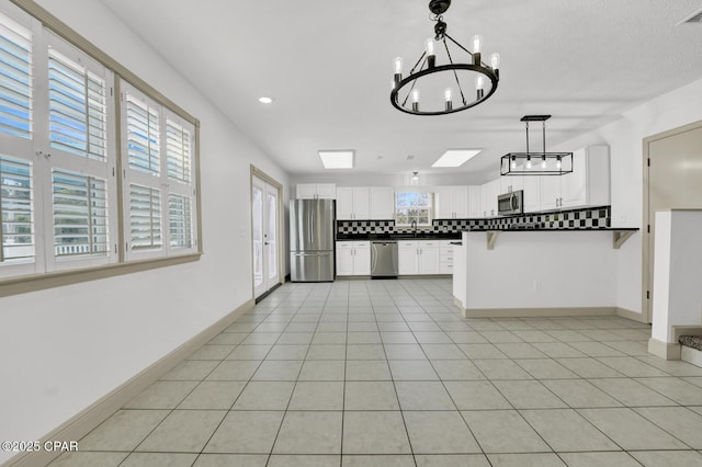 8508 S Holland Rd, Southport, FL 32409 - kitchen featuring appliances with stainless steel finishes, dark countertops, a chandelier, a sink, and white cabinetry