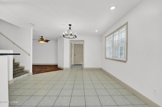 8508 S Holland Rd, Southport, FL 32409 - empty room featuring light tile patterned floors, a chandelier, a ceiling fan, stairs, and recessed lighting