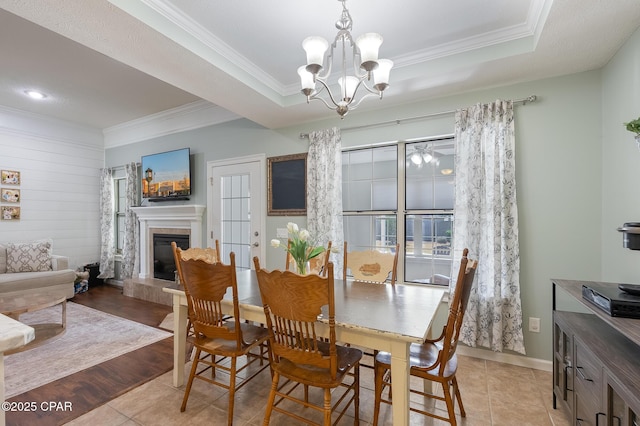 3543 Brentwood Pl, Panama City, FL 32404 - dining room with ornamental molding, a chandelier, a glass covered fireplace, a raised ceiling, and light tile patterned floors
