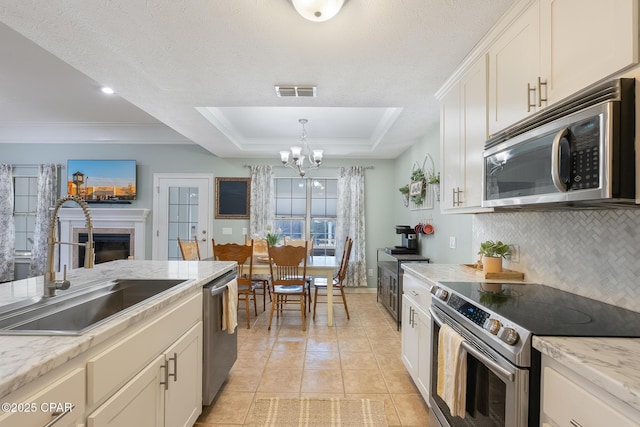 3543 Brentwood Pl, Panama City, FL 32404 - kitchen featuring appliances with stainless steel finishes, a sink, a raised ceiling, a chandelier, and a fireplace