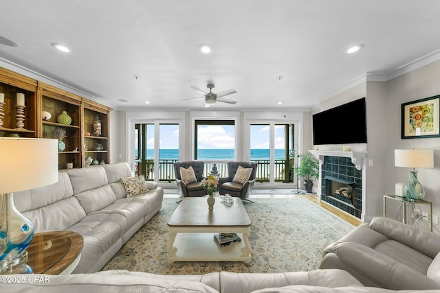 living area with crown molding, recessed lighting, a ceiling fan, healthy amount of natural light, and a high end fireplace