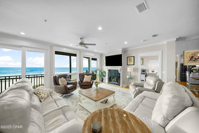 living area featuring a ceiling fan, ornamental molding, healthy amount of natural light, recessed lighting, and a water view