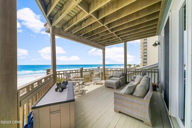 wooden terrace featuring view of water and beach and an outdoor hangout area