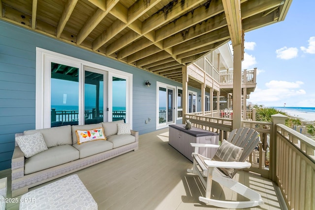 balcony featuring an outdoor hangout area, a deck with water view, and view of local beach