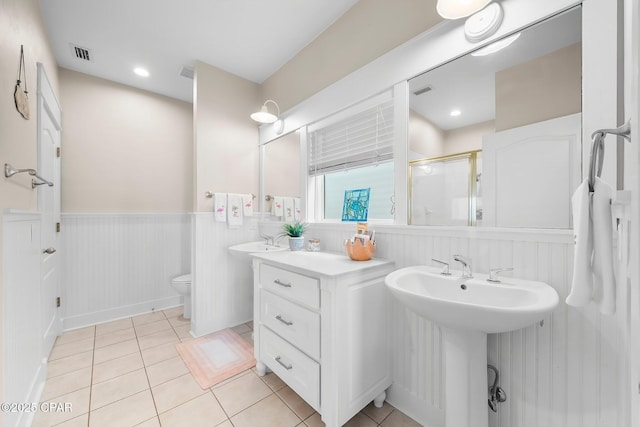 bathroom with a shower stall, wainscoting, tile patterned floors, and toilet