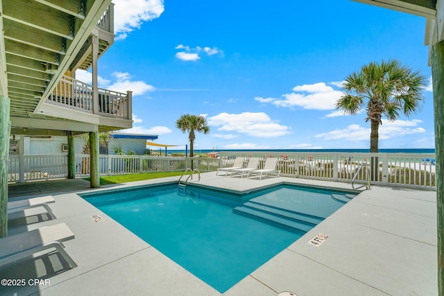 community pool featuring fence, a water view, and a patio area