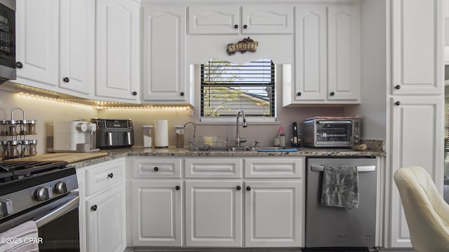 722 E Pine Forest Dr, Lynn Haven, FL 32444 - kitchen with stainless steel appliances, a sink, white cabinets, and dark stone countertops