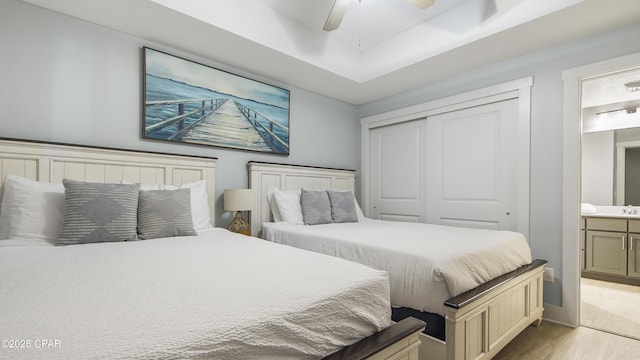 bedroom featuring a closet, ceiling fan, ensuite bathroom, and light wood-style flooring