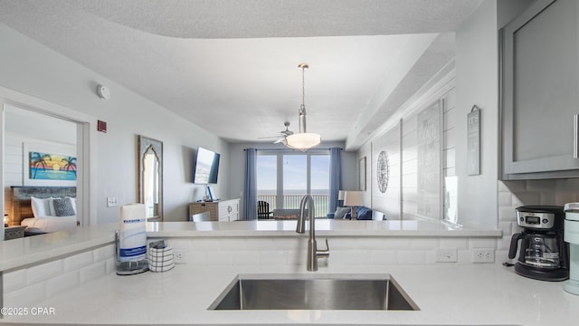 kitchen with a sink, open floor plan, light countertops, a ceiling fan, and gray cabinets