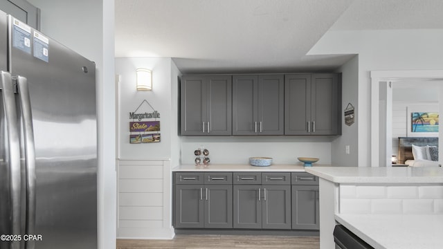 kitchen with freestanding refrigerator, light wood-type flooring, gray cabinets, and light countertops