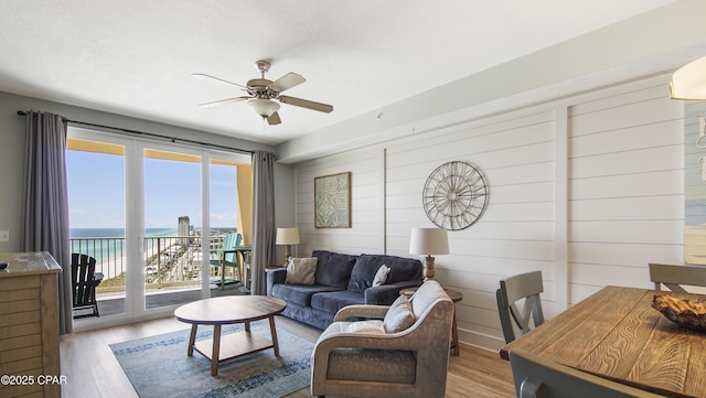 living room featuring wood finished floors, a ceiling fan, and a water view