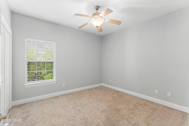 carpeted empty room featuring baseboards and a ceiling fan