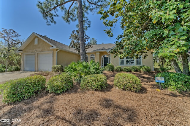 ranch-style home featuring stucco siding, an attached garage, and driveway