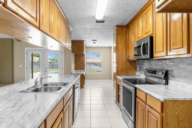 7936 Betty Louise Dr, Panama City, FL 32404 - kitchen with appliances with stainless steel finishes, a sink, decorative backsplash, brown cabinetry, and light tile patterned floors