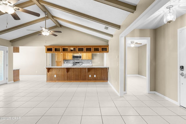 7936 Betty Louise Dr, Panama City, FL 32404 - kitchen featuring appliances with stainless steel finishes, ceiling fan, light countertops, a kitchen bar, and beam ceiling