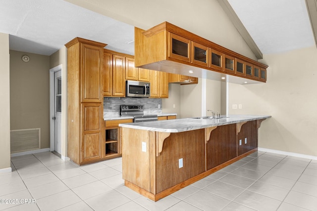 7936 Betty Louise Dr, Panama City, FL 32404 - kitchen with appliances with stainless steel finishes, a peninsula, glass insert cabinets, a breakfast bar, and backsplash