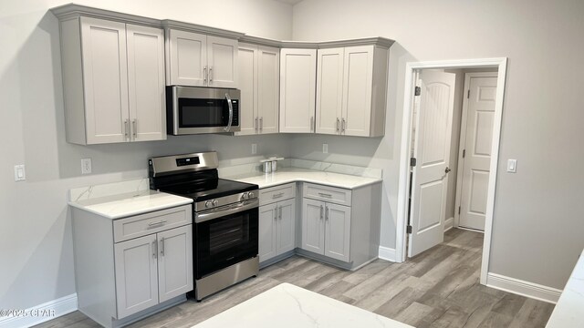 11438 Palm Breeze St, Panama City, FL 32404 - kitchen featuring stainless steel appliances, gray cabinets, light wood-style flooring, and baseboards