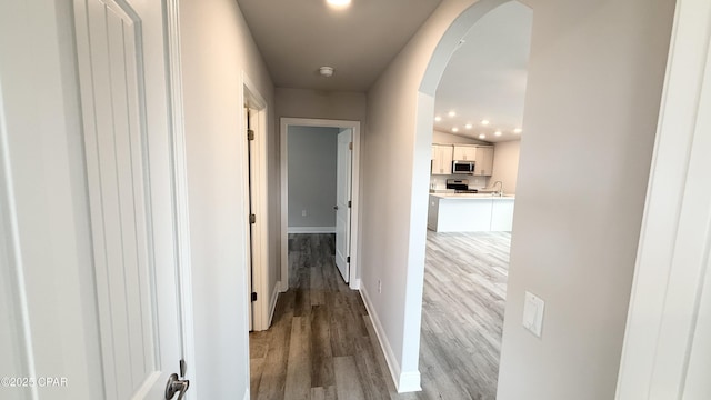 11442 Palm Breeze St, Panama City, FL 32404 - hallway featuring light wood-style flooring, arched walkways, baseboards, a sink, and recessed lighting
