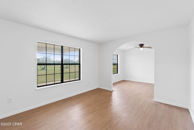 10367 NW County Road 274, Altha, FL 32421 - empty room featuring light wood-type flooring, arched walkways, ceiling fan, and baseboards