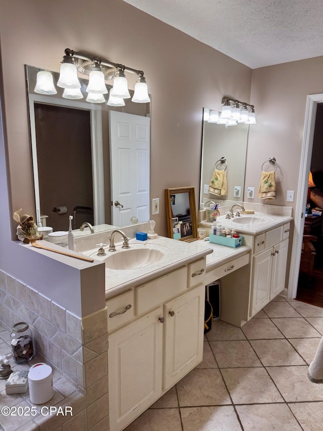 full bath with tile patterned floors, a textured ceiling, and two vanities