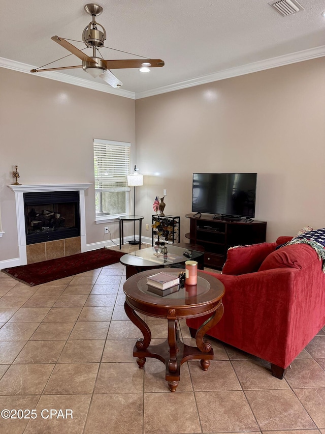 living area featuring ornamental molding, baseboards, ceiling fan, a fireplace, and tile patterned floors