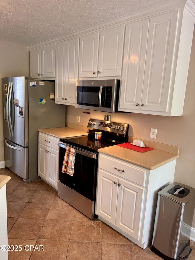 kitchen featuring appliances with stainless steel finishes, white cabinets, light countertops, light tile patterned floors, and a textured ceiling