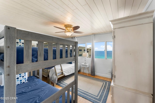 bedroom featuring wood ceiling, a water view, wood finished floors, and ceiling fan