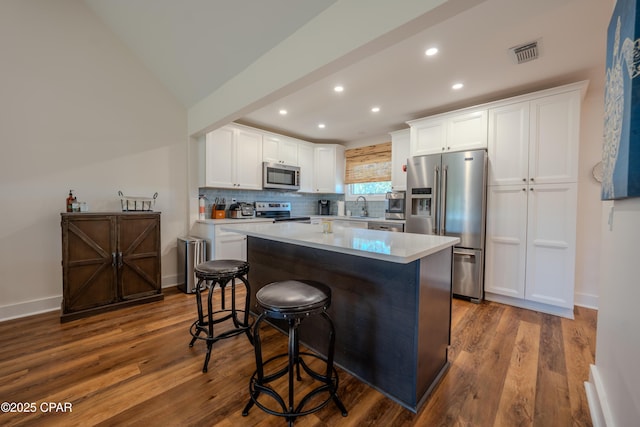 kitchen featuring stainless steel appliances, recessed lighting, a sink, a center island, and dark wood-style flooring