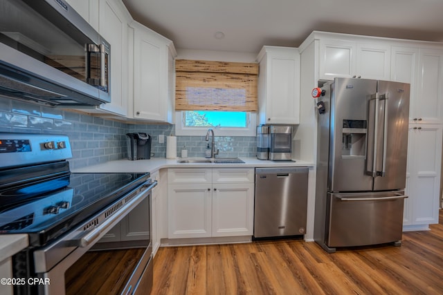 kitchen with stainless steel appliances, a sink, light countertops, light wood-type flooring, and white cabinets