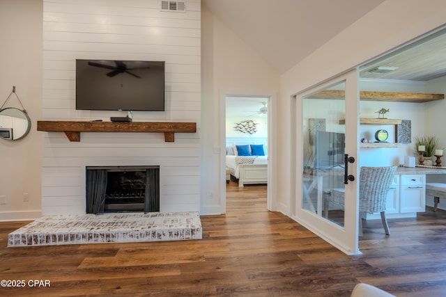 living room with wood finished floors, a desk, vaulted ceiling, a fireplace, and a ceiling fan