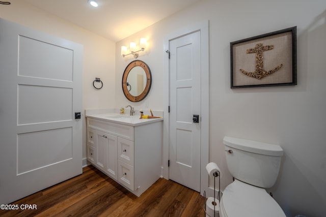 bathroom with wood finished floors, toilet, and vanity