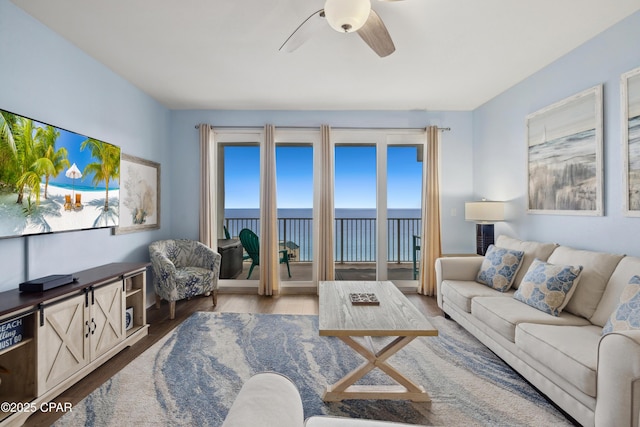 living room with a ceiling fan, wood finished floors, and a water view
