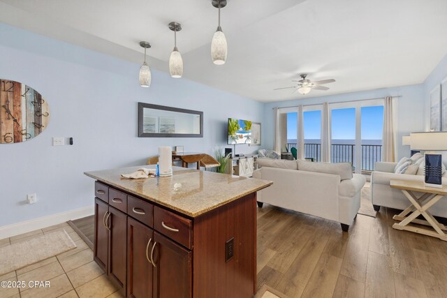 9860 S Thomas Dr Unit 1824, Panama City Beach, FL 32408 - kitchen featuring a ceiling fan, pendant lighting, open floor plan, light stone countertops, and light wood-style flooring