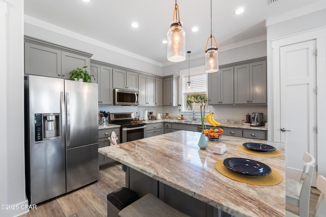111 George C Wallace Blvd, Panama City Beach, FL 32413 - kitchen with appliances with stainless steel finishes, gray cabinets, a breakfast bar area, light stone countertops, and recessed lighting