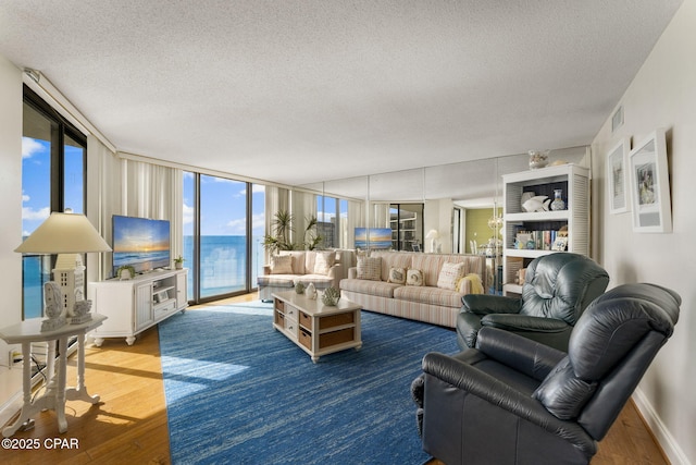 living room featuring a textured ceiling, wood finished floors, floor to ceiling windows, and baseboards