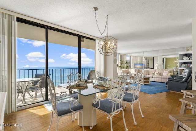 dining room featuring a chandelier, expansive windows, a textured ceiling, and wood finished floors